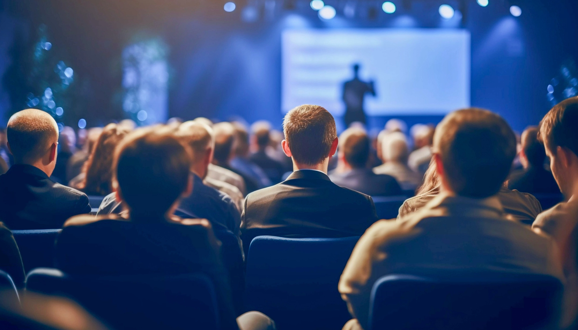 Plateia assistindo a uma apresentação executiva projetada em telão